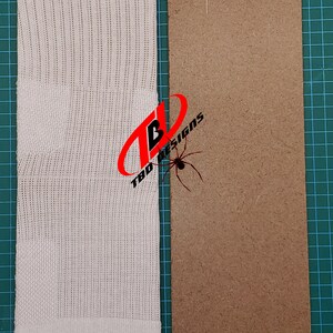 May include: A white sock with a small black logo on the heel, next to a brown piece of cardboard.