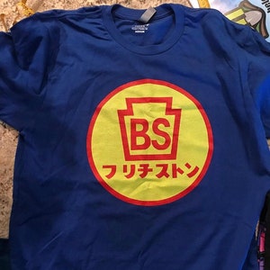 May include: A blue t-shirt with a yellow and red circle logo. The logo features a red outline of the state of Pennsylvania with the letters "BS" inside. The text "フ リ チ ェ ス ト ン" is written in Japanese below the logo.