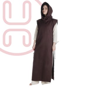 May include: A brown hooded medieval tunic with a sleeveless design. The tunic has a long, flowing skirt and a hood that drapes around the neck. The model is wearing a light-colored shirt and pants underneath the tunic.