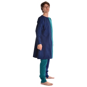 May include: A person wearing a long-sleeved tunic with a blue and green color block design. The tunic has a round neckline and is knee-length. The person is wearing matching green pants.