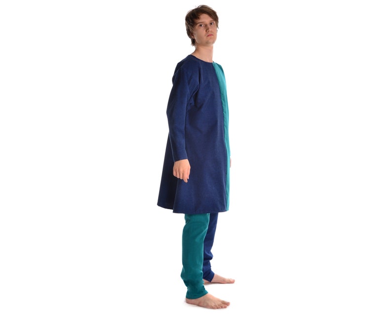 May include: A person wearing a long-sleeved tunic with a blue and green color block design. The tunic has a round neckline and is knee-length. The person is wearing matching green pants.