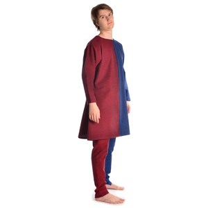 May include: A person wearing a long-sleeved tunic with a red and blue color block design. The tunic has a simple, loose fit and is made of a soft, textured fabric.