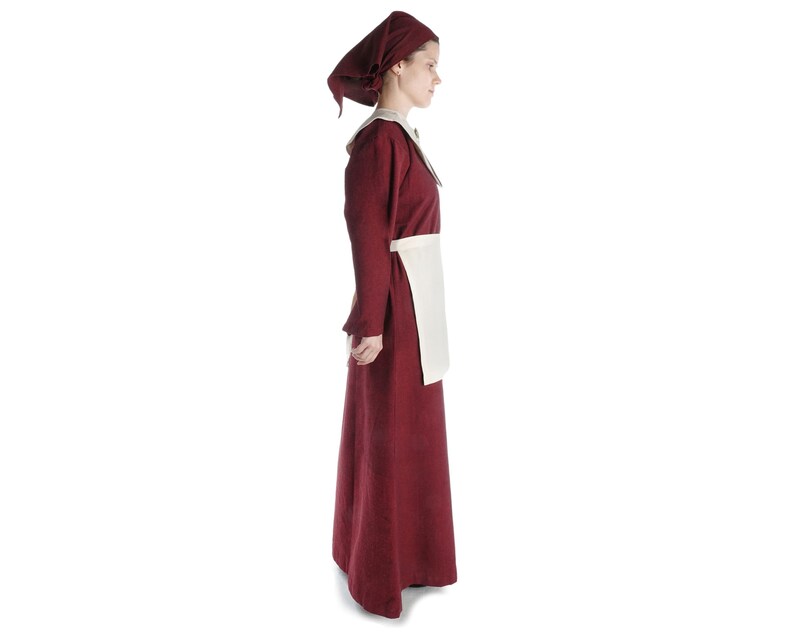 May include: A woman wearing a long, burgundy dress with a white apron and a burgundy headscarf.
