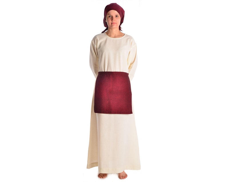 May include: A woman wearing a long, white tunic with a burgundy apron and a burgundy headscarf.