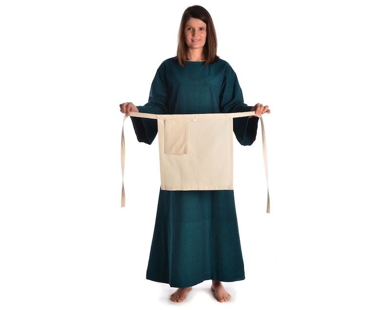 May include: A teal tunic with long sleeves and a white apron with a pocket. The apron is tied at the waist with long ties.