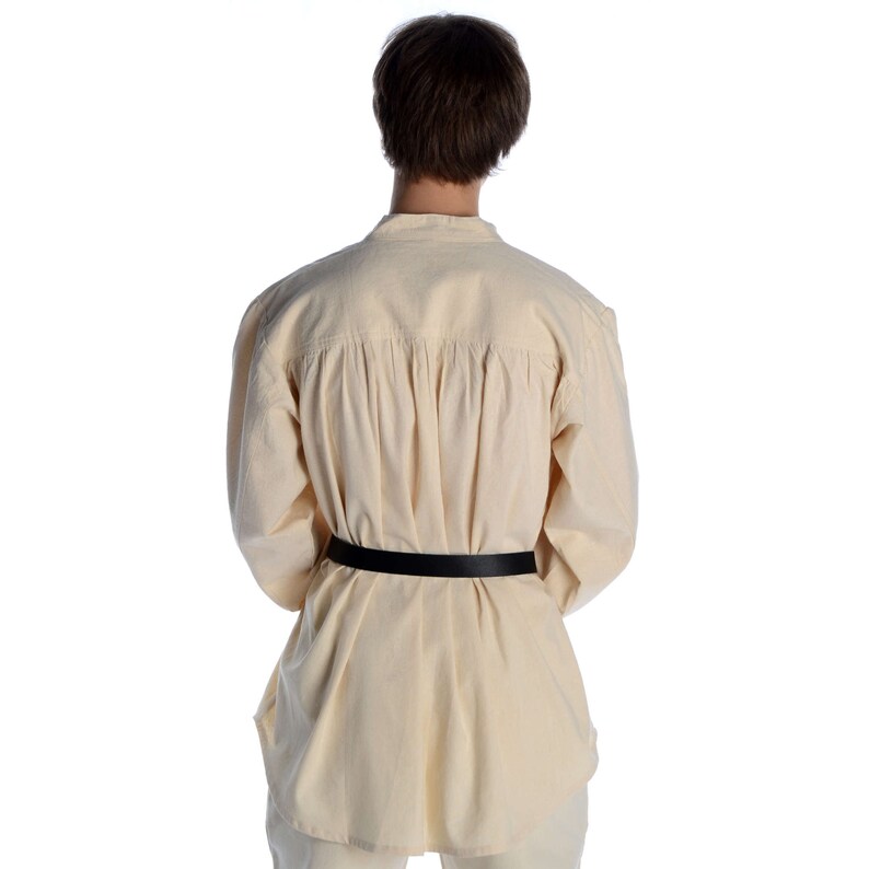 Pode incluir: Uma camisa creme de manga comprida com um cinto preto. A camisa tem gola mandarim e pregas nas costas. O cinto &eacute; feito de couro preto. A camisa &eacute; feita de um tecido leve e respir&aacute;vel.