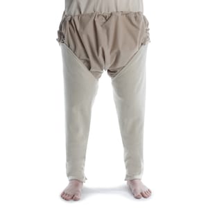 Könnte beinhalten: Eine weiße Leinenleggings mit einem gerafften, beigefarbenen Stoffbund.