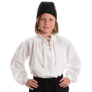 Może przedstawiać: Biała koszula z długim rękawem, z koronkowym dekoltem i czarnym kapeluszem pirata. Koszula ma bufiasty rękaw i marszczony dekolt.