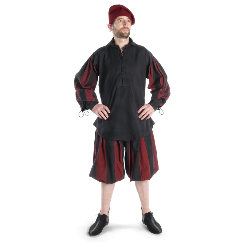 May include: A man wearing a black and red striped shirt and matching shorts with a red beret.