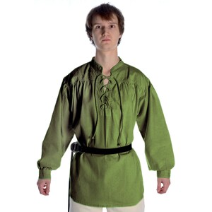 Pode incluir: T&uacute;nica verde-oliva de manga comprida com decote com atacadores e cinto preto. A t&uacute;nica tem um corte solto com detalhes franzidos nos ombros e punhos. A pe&ccedil;a de vestu&aacute;rio &eacute; feita de um tecido texturizado, adequado para reconstitui&ccedil;&otilde;es hist&oacute;ricas ou fantasias.