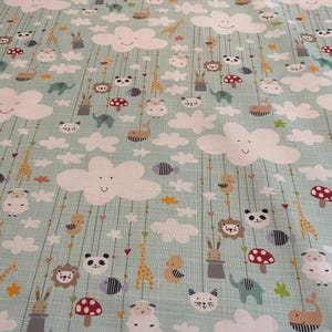 May include: Light blue fabric with a repeating pattern of white smiling clouds, various animals, and red mushrooms. The animals include giraffes, pandas, lions, and elephants. The design is whimsical and suitable for children's items.