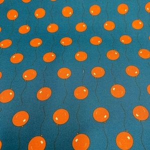 May include: A teal fabric with a repeating pattern of orange balloons. The balloons have a simple, rounded shape and are attached to strings.