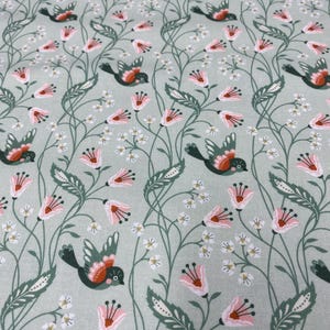 May include: A green fabric with a repeating pattern of pink flowers, green leaves, and small birds. The birds are stylized and have red, orange, and yellow accents.