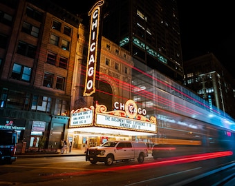 May include: A white pickup truck parked in front of a building with a large sign that reads "Chicago" and "The Basement Yard Experience." The sign also includes the dates "July 15" and "Aug 18".