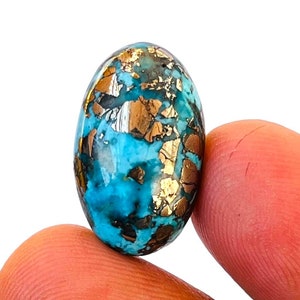 May include: Oval shaped turquoise cabochon with gold pyrite inclusions. The stone is a vibrant blue with flecks of gold throughout.