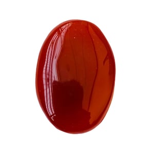 Puede incluir: Una piedra de cornalina lisa de forma ovalada, de color rojo oscuro y con un acabado brillante.