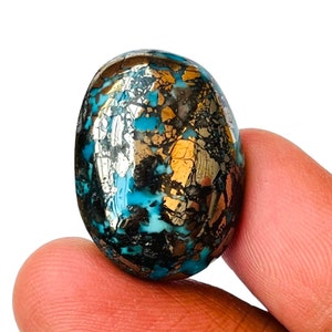 May include: A smooth, oval-shaped turquoise stone with a unique pattern of gold and black pyrite inclusions. The stone has a vibrant blue color and a polished finish.
