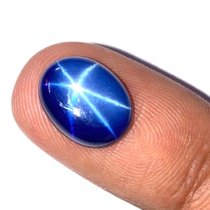 Könnte beinhalten: Ein blauer Stern-Saphir-Edelstein mit einem sternförmigen Muster in der Mitte.