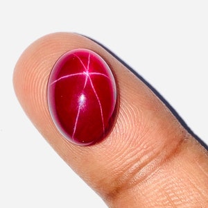 May include: A deep red star ruby cabochon gemstone with a starburst pattern.