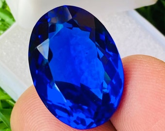 May include: A large, oval-shaped, deep blue gemstone with a faceted cut.