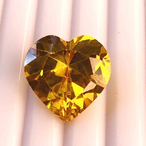 May include: A heart-shaped, yellow gemstone with a faceted cut.