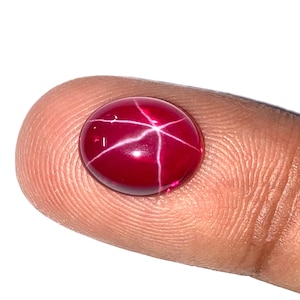 May include: A red star ruby gemstone with a starburst pattern.