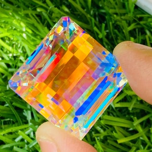 Può includere: Un cristallo iridiscente di forma quadrata con colori arcobaleno, tra cui arancione, blu e verde.