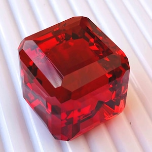 Può includere: Un fermacarte quadrato in cristallo rosso scuro sfaccettato.