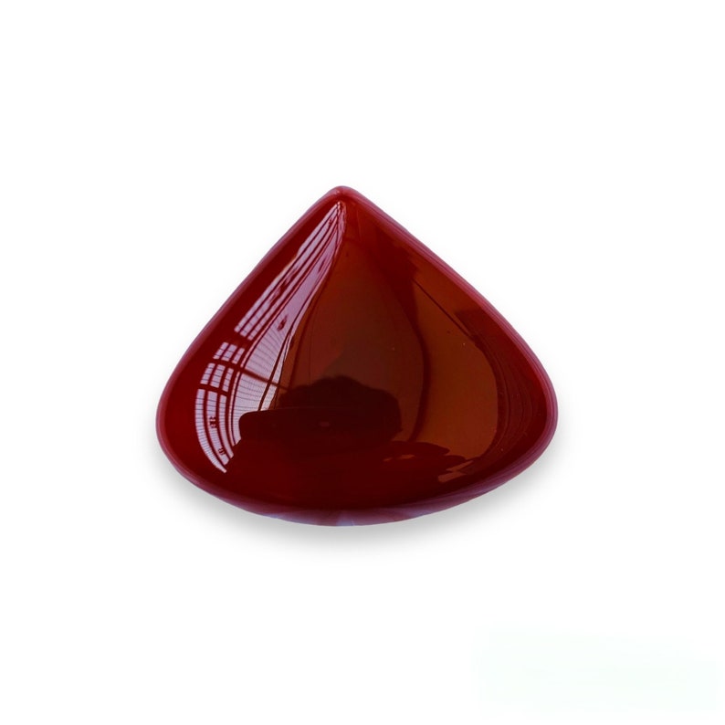 May include: A deep red, teardrop-shaped gemstone with a smooth, polished surface.