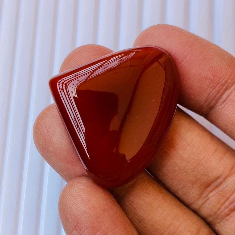 May include: A smooth, polished, red carnelian gemstone in a heart shape.