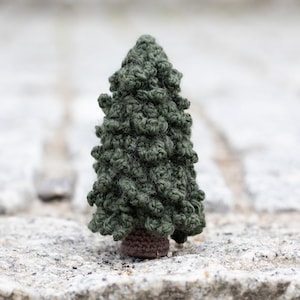 Peut inclure: Un petit arbre de pin vert en crochet avec une base brune.