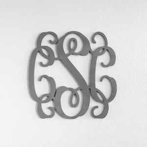 May include: A silver metal monogram with the letters "S C" intertwined in a decorative script font.