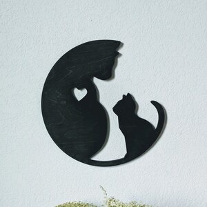 May include: Black wooden wall decor featuring a silhouette of two cats, one larger than the other, with a heart shape between them.