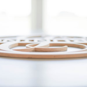 May include: Close-up of a wooden wall decor with a circular design. The design is made of multiple layers of wood, creating a three-dimensional effect.
