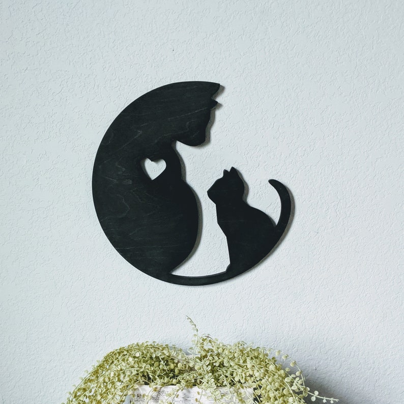 May include: Black wooden wall decor featuring a silhouette of two cats, one larger than the other, with a heart shape between them.