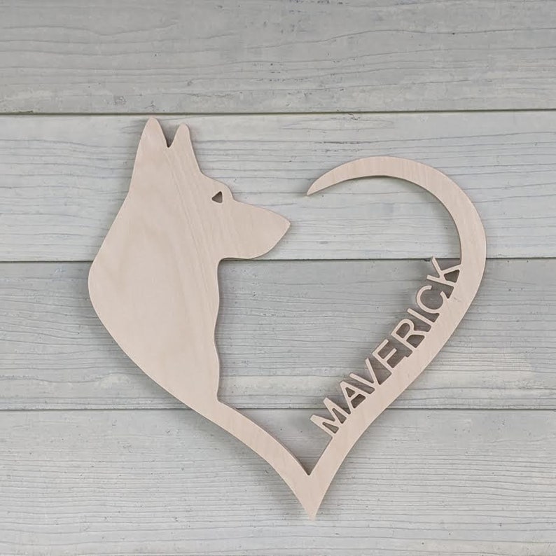 May include: A wooden heart-shaped cutout with a dog silhouette and the name "Maverick" inscribed inside the heart.
