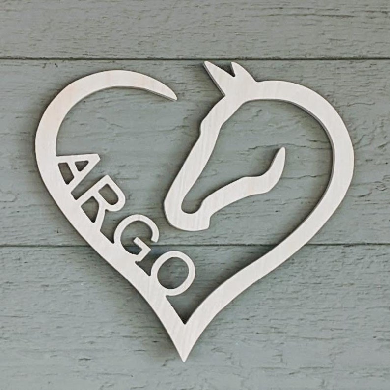 May include: A white wooden heart-shaped sign with a horse head silhouette and the name "ARGO" cut out inside.