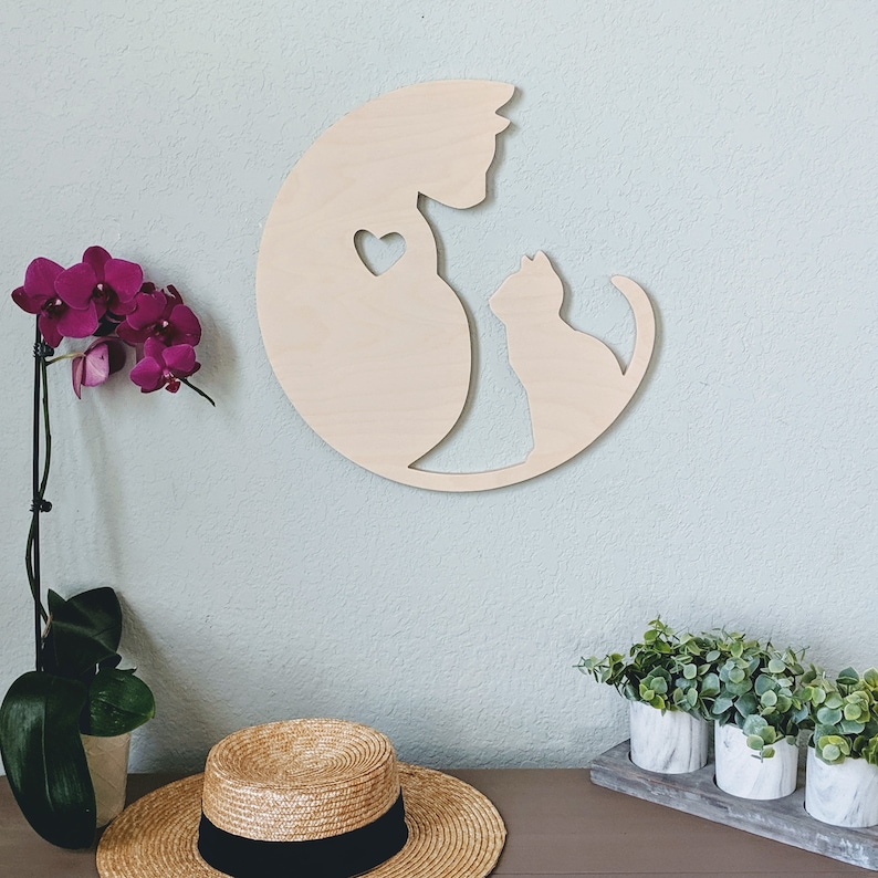 May include: Wooden wall decor featuring a silhouette of two cats, one larger than the other, with a heart shape in the larger cat's chest. The cats are facing each other and appear to be cuddling.