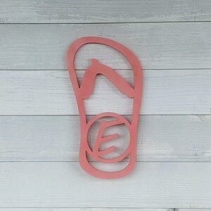 May include: A pink wooden cutout of a flip-flop sandal with a leaf design in the center.