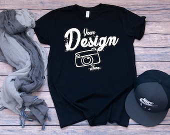 May include: Black t-shirt with white text that says "Your Design -Here- " and a white outline of a camera.