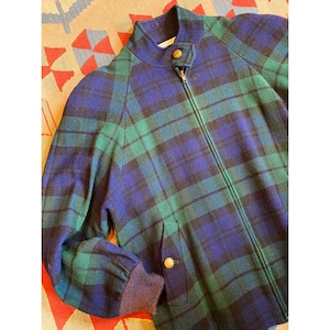May include: A zip-up jacket featuring a blue and green plaid pattern. The jacket has a high collar with a single snap button closure, long sleeves with ribbed cuffs, and two front pockets, each secured with a single round tan snap button.