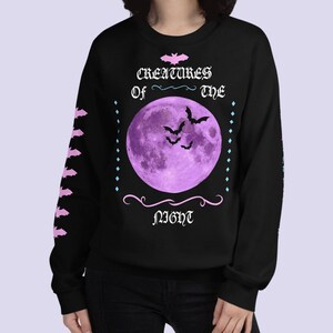 May include: Black sweatshirt with a purple moon and bats graphic. The text reads "Creatures of the Night".