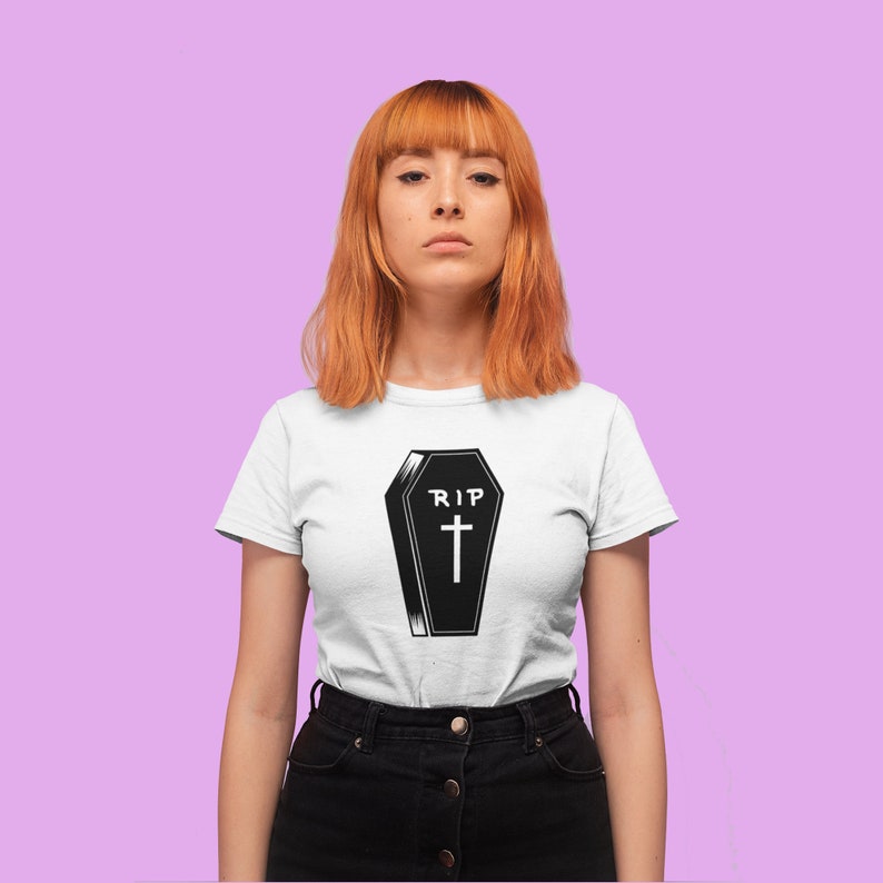 K&ouml;nnte beinhalten: Ein wei&szlig;es T-Shirt mit einer schwarz-wei&szlig;en Illustration eines Sarges mit dem Text "RIP" und einem Kreuz.