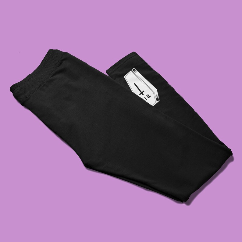 May include: Black leggings with a white graphic of a coffin with a cross and the letters "R.I.P."