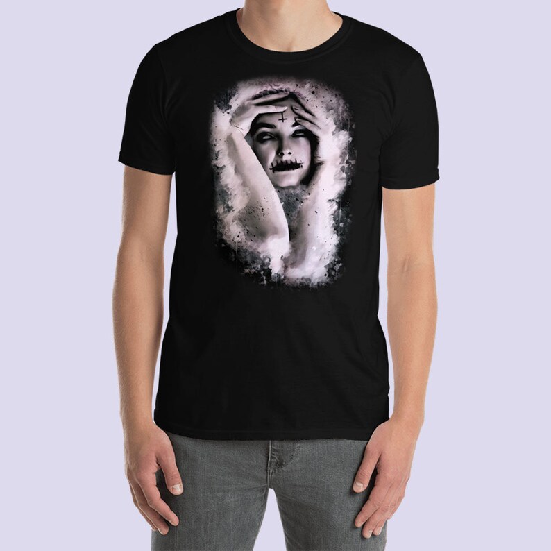 May include: Black t-shirt with a watercolor-style image of a woman with her hands covering her face. The woman has a cross drawn on her forehead.