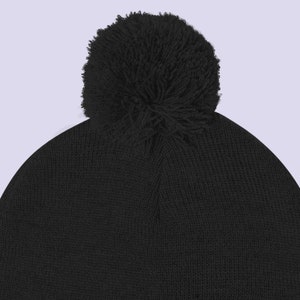 May include: A black knit beanie with a fluffy black pom pom on top.