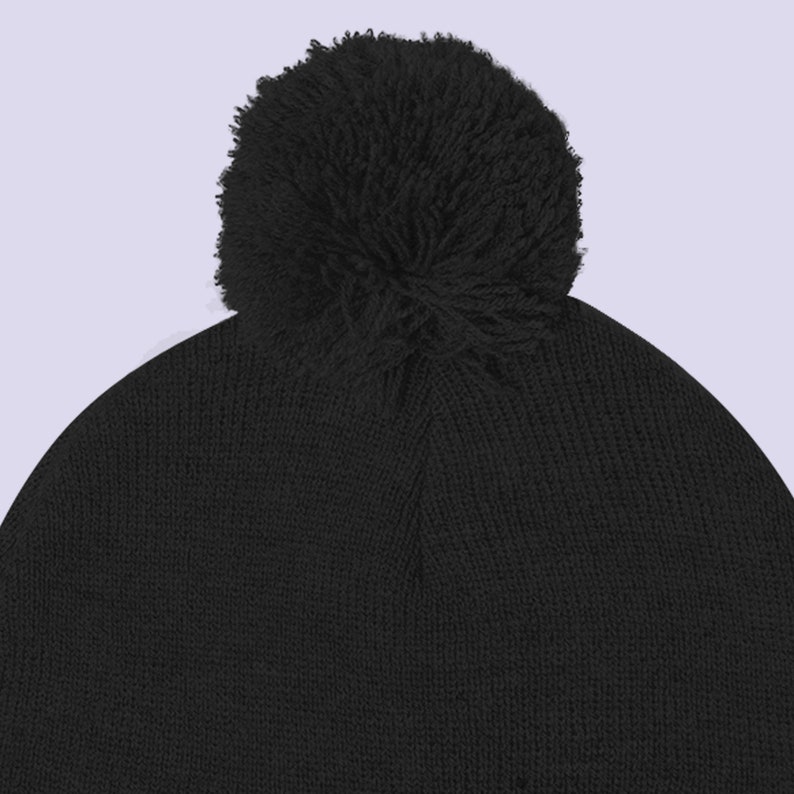 May include: A black knit beanie with a fluffy black pom pom on top.