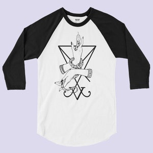 K&ouml;nnte beinhalten: Ein wei&szlig;-schwarzes Baseball-T-Shirt mit einer schwarz-wei&szlig;en Illustration einer Hand, die eine Schlange, ein Pentagramm und den Text "XV" h&auml;lt.