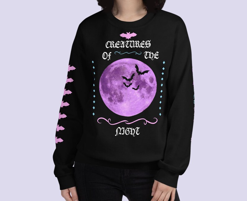 May include: Black sweatshirt with a purple moon and bats graphic. The text reads "Creatures of the Night".