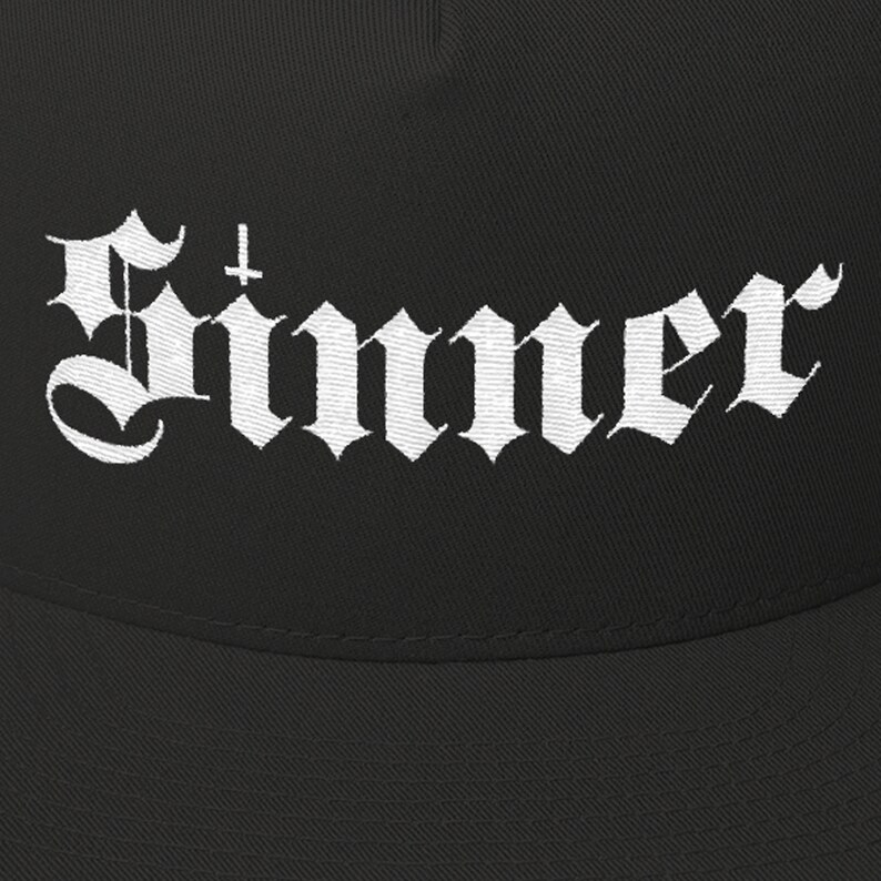 Puede incluir: Gorra de b&eacute;isbol negra con un dise&ntilde;o bordado en blanco que dice "Sinner" con una cruz sobre la primera letra.